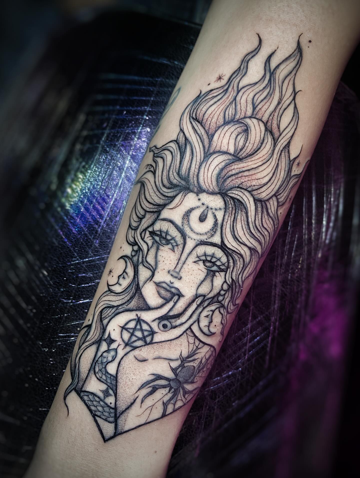 Tatuaje gótico de bruja con cabello flameante, pentagrama y araña en el antebrazo