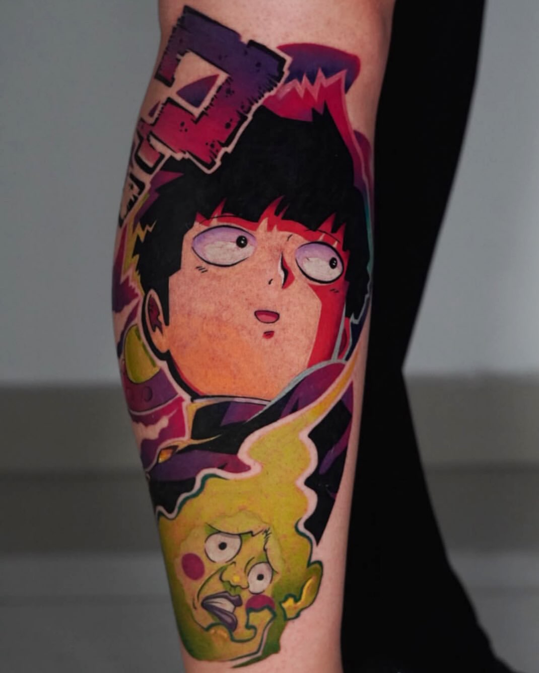 Tatuaje a color de Mob de Mob Psycho 100 en la pantorrilla, con aura verde y letras rojas