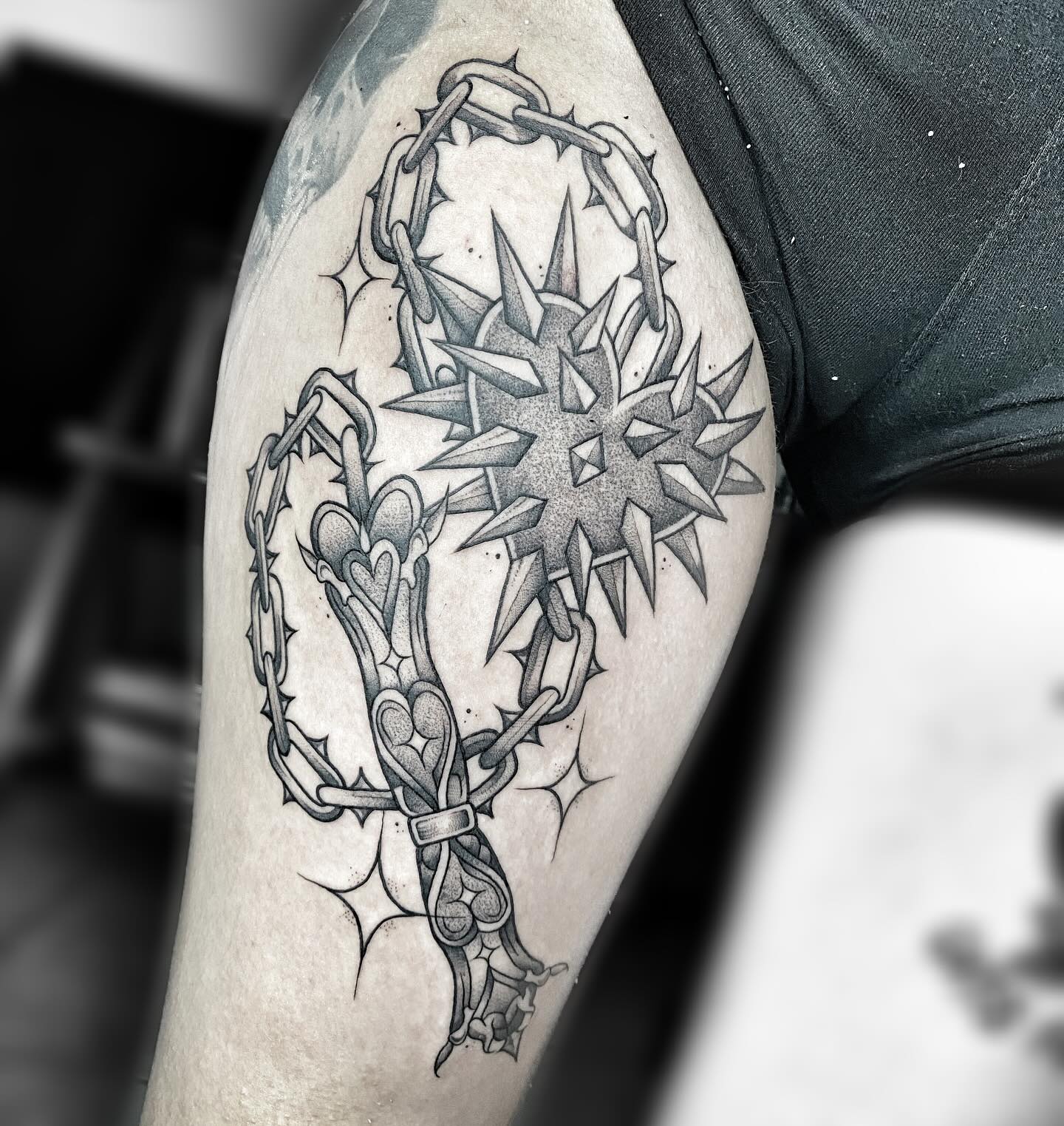Tatuaje de cadena espinada con corazones y una maza central en negro y gris