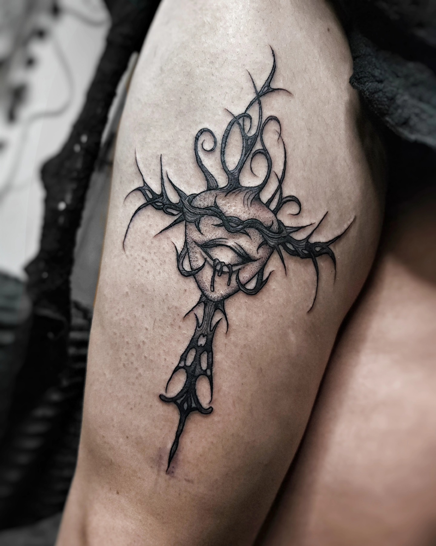 Tatuaje de corazón anatómico atravesado por formas ornamentales espinadas en el brazo