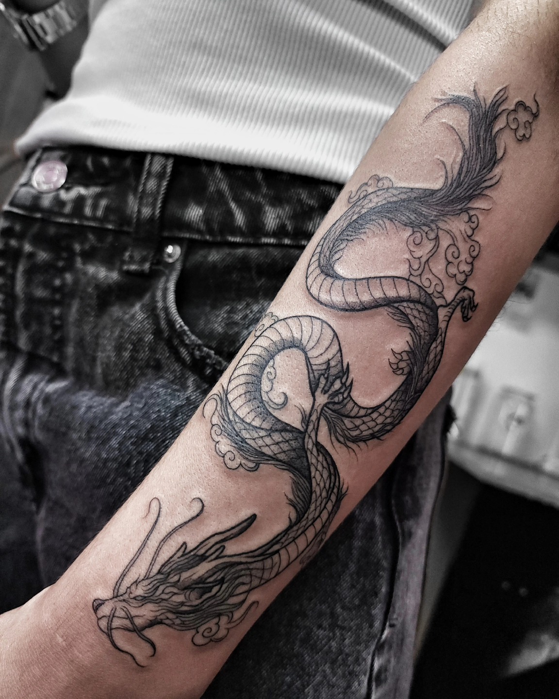 Tatuaje de dragón oriental alargado en negro y gris recorriendo el antebrazo