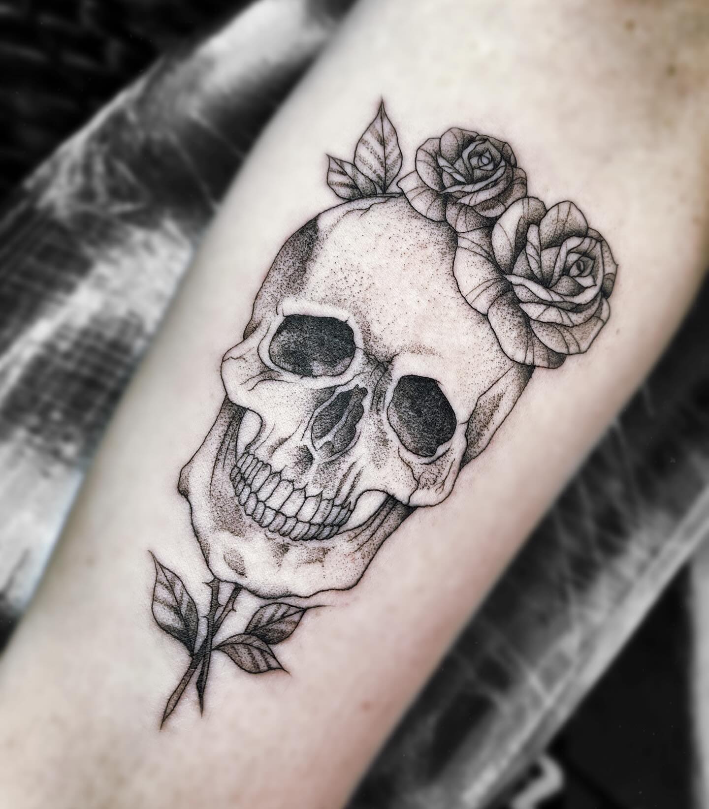 Tatuaje de calavera con rosas realizado en puntillismo negro y gris