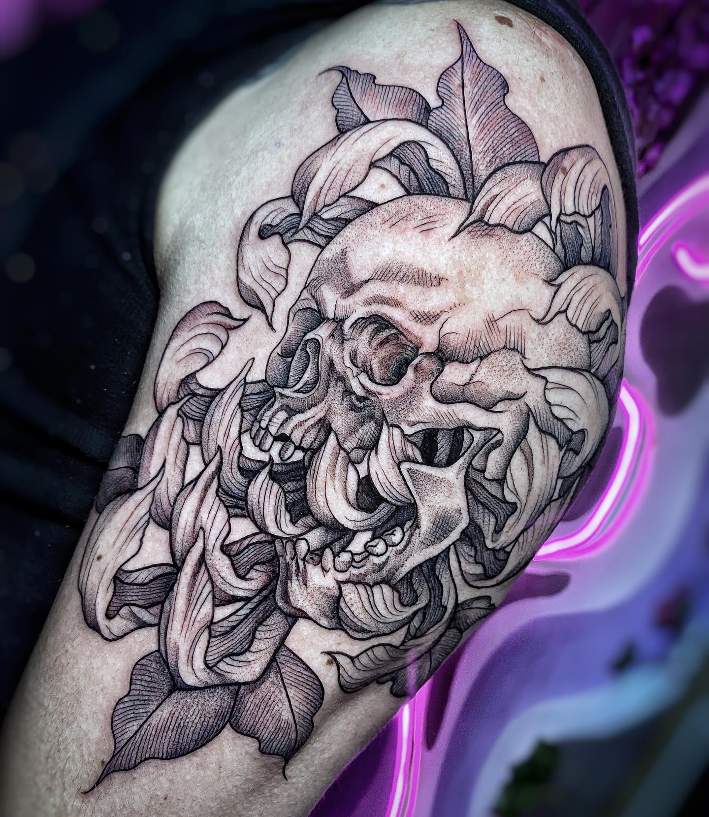 Tatuaje de dos calaveras entre flores con sombreado de puntillismo en el brazo