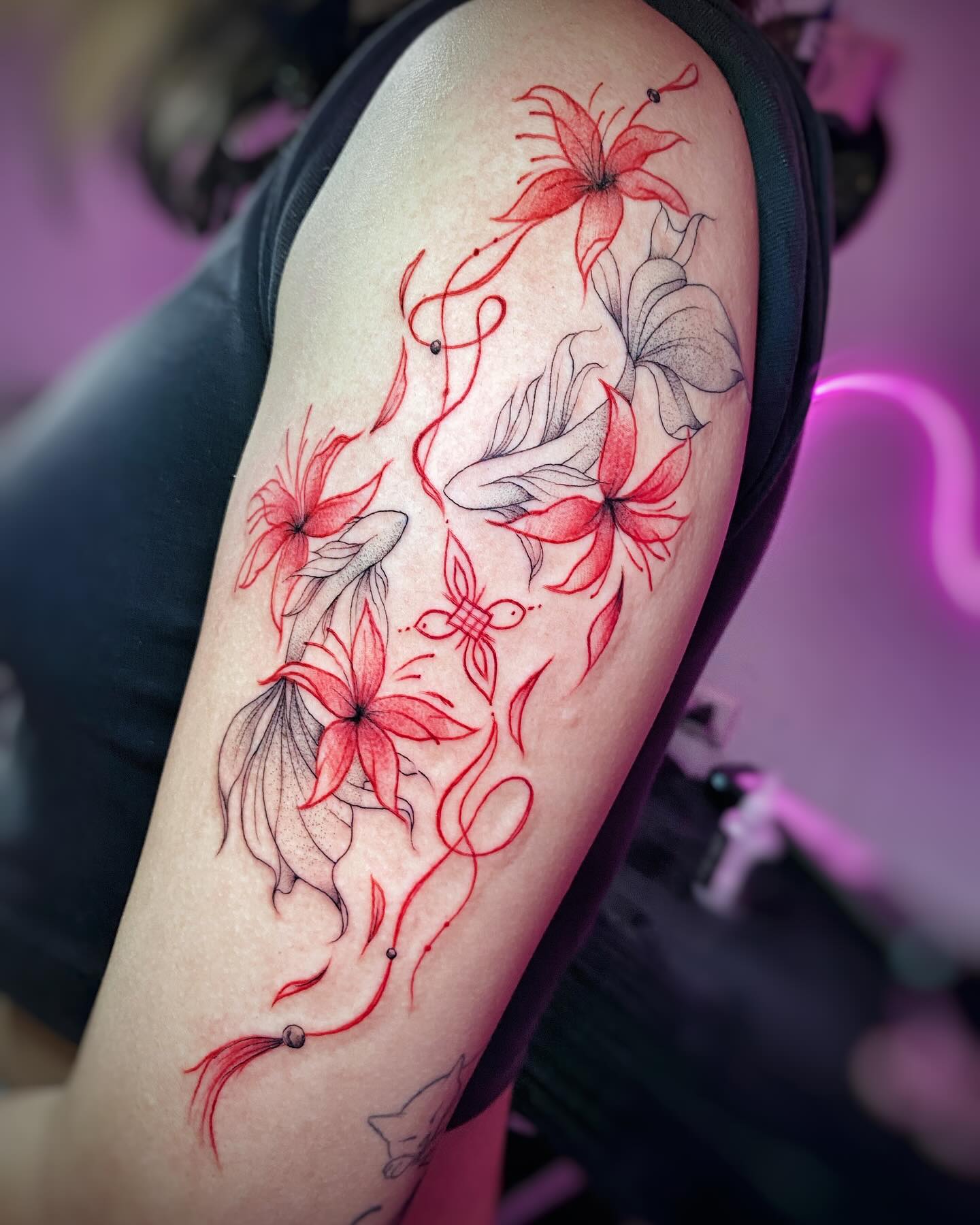 Tatuaje floral en líneas finas negras y rojas con ornamentos sobre el brazo