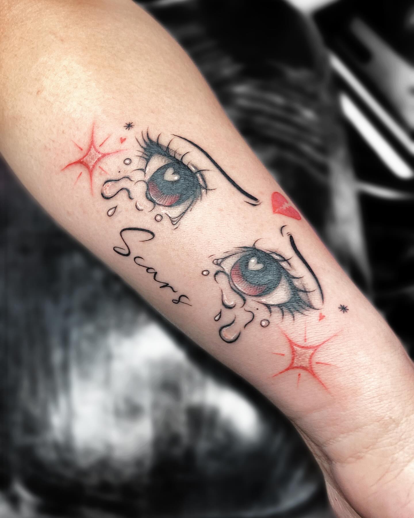 Ojos estilo anime con lágrimas, corazones y destellos rojos en el antebrazo
